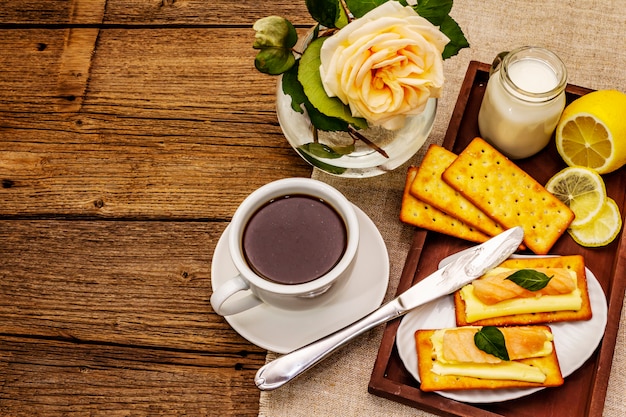 Colazione salutare. Tazza di caffè (tè nero), latte, crackers con burro e salmone