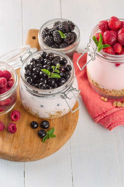 Colazione salutare. Yogurt al muesli con fragole, mirtilli, more e lamponi fatti in casa in un barattolo di vetro nella cucina di casa