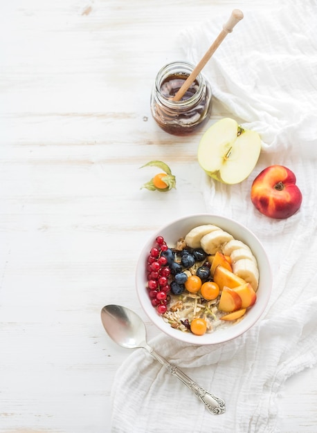 Colazione sana Ciotola di muesli d'avena con yogurt, frutti di bosco freschi, frutta e miele Vista dall'alto