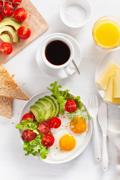 Colazione sana e distesa. uova fritte, avocado, pomodoro, toast e caffè