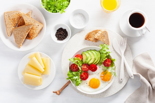 Colazione sana e distesa. uova fritte, avocado, pomodoro, toast e caffè