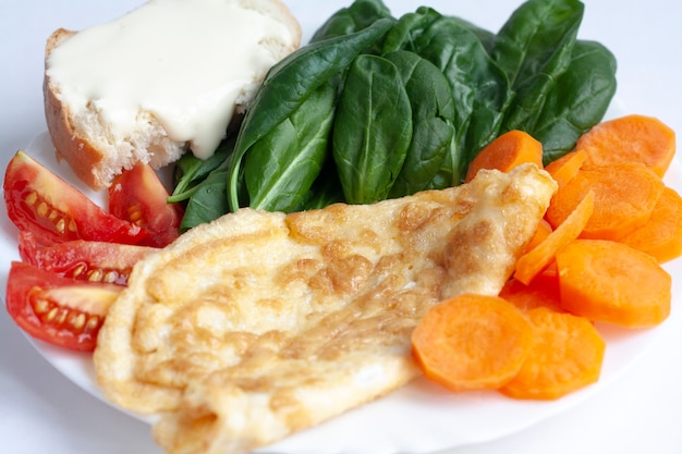 Colazione sana, frittata, verdure spinaci, pomodori e carote e un panino con formaggio morbido