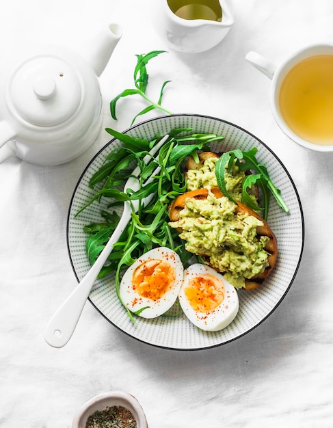 Colazione sana o spuntino insalata di rucola con uova sode e toast di avocado su sfondo chiaro