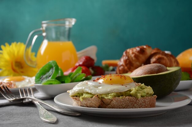 Colazione sana Toast con avocado e uova, pancetta e uova, frutta fresca e secca, succo fresco