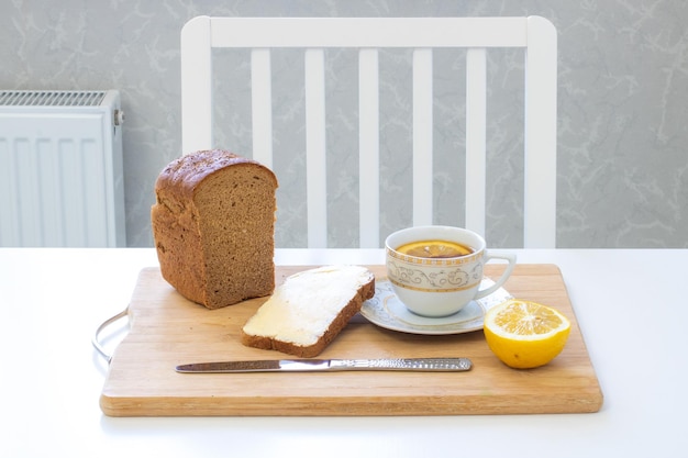 Colazione su fondo di legno con tè al limone e pane al burro