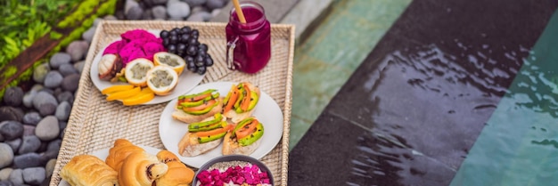 Colazione su un vassoio con panini alla frutta panini con avocado ciotola di frullato a bordo piscina dieta sana estiva