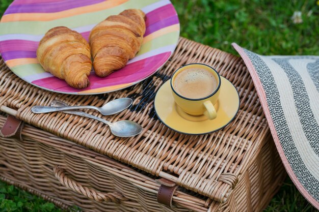 Colazione sull'erba. Tazza di caffè e croissant francesi. Sfondo romantico data
