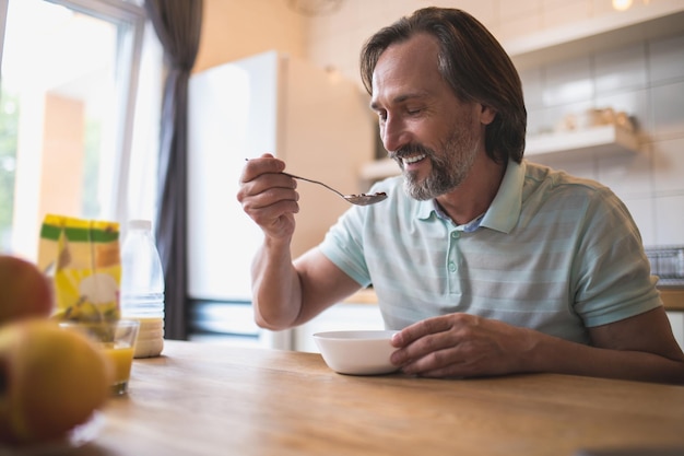 Colazione. Uomo caucasico maturo seduto al tavolo e mangiare la colazione