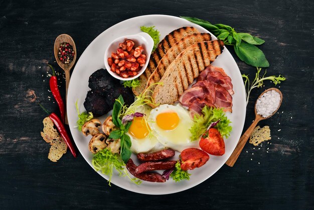 Colazione Uova con pancetta e pomodori pane tostato Vista dall'alto su uno sfondo di legno Copia spazio