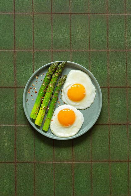 Colazione uova fritte con asparagi freschi e jamon e erbe in un piatto