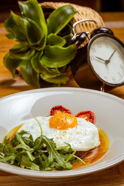 Colazione uova fritte con rucola bistecca e pomodori secchi