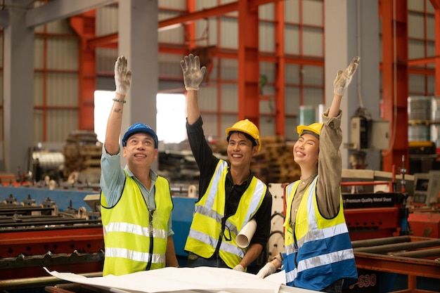 Collaboratori del lavoro di squadra Tecnici e ingegneri con elmetto protettivo o giubbotto da casco che mostrano la coordinazione delle mani e alzano il pugno sorridendo per lavorare con successo nel posto di lavoro dell'industria Fabbrica