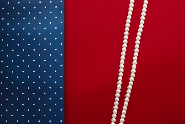 Collana di gioielli di perle e sfondo astratto a pois blu su sfondo rosso