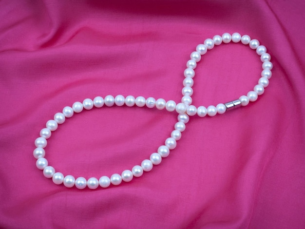Collana di perle bianche su materiale satinato di seta viola