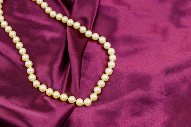 Collana di perle su fondo in tessuto satinato viola