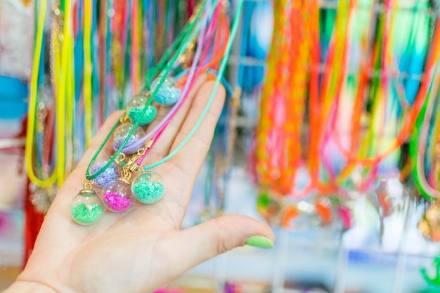 Collane di perline di gioielli imitazione da donna sulla vetrina del commercio di strada La mano di una donna sceglie le perline