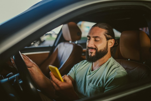 Collegato Giovane uomo dai capelli scuri bello con un telefono in mano