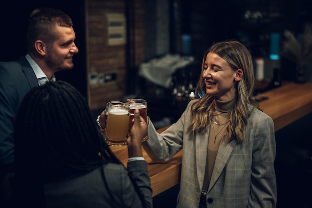 Colleghi allegri che bevono birra al bar insieme dopo il lavoro