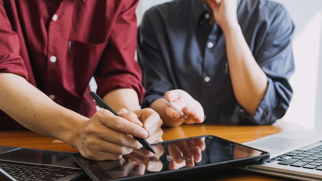 Colleghi asiatici uomo e donna che discutono e lavorano con il computer portatile sulla scrivania dell'ufficio