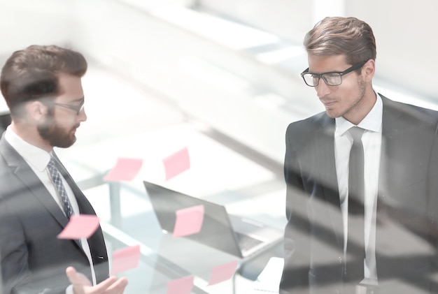 Colleghi di lavoro che discutono di note adesive su vetro