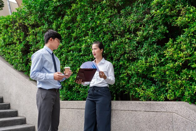 Colleghi di lavoro che discutono di problemi di lavoro all'aperto vicino all'edificio per uffici, parlando tra loro all'aperto.