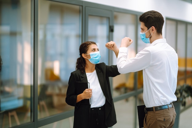 Colleghi di lavoro che urtano i gomiti mentre si salutano al lavoro.