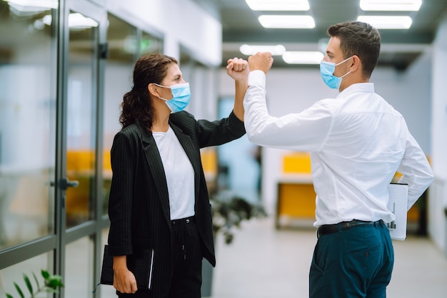 Colleghi di lavoro che urtano i gomiti mentre si salutano al lavoro.