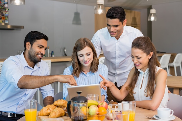 Colleghi di lavoro discutendo su tavoletta digitale mentre si consuma la colazione