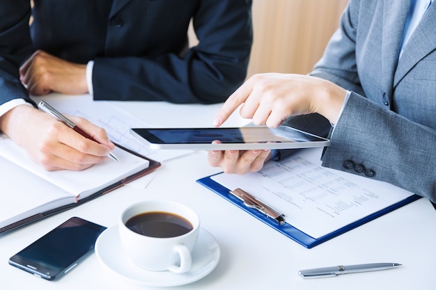 Colleghi di lavoro irriconoscibili che lavorano insieme e utilizzano un tablet digitale