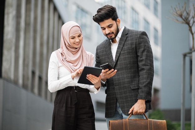 Colleghi di lavoro musulmani che utilizzano gadget moderni all'aperto