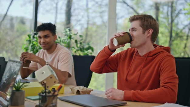 Colleghi sorridenti che bevono caffè che si godono la pausa in ufficio primo piano della squadra che parla