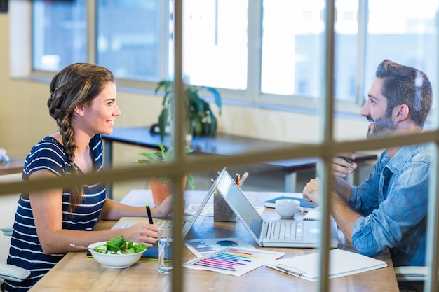 Colleghi sorridenti che lavorano insieme sul computer portatile e sulla discussione