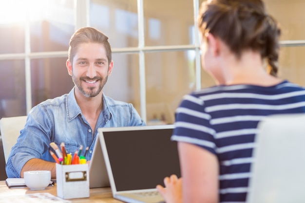 Colleghi sorridenti che lavorano insieme sul computer portatile