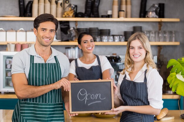 Colleghi sorridenti che mostrano lavagna con il segno aperto