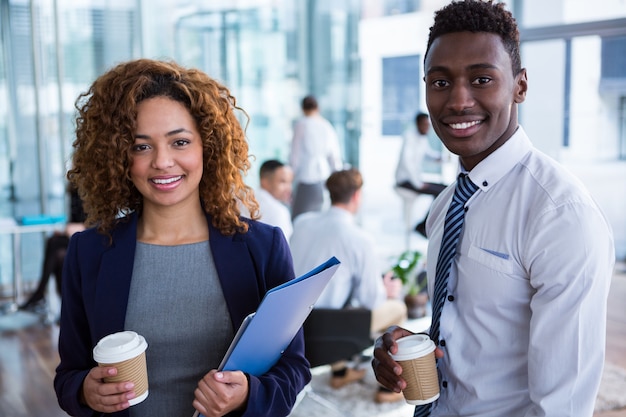 Colleghi sorridenti di affari che mangiano caffè in ufficio