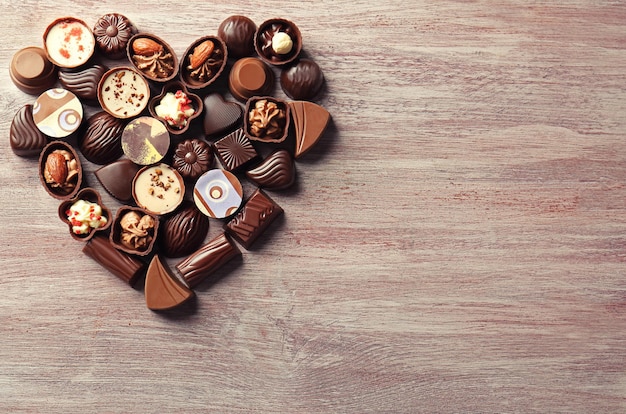 Collezione a forma di cuore di caramelle al cioccolato su fondo di legno