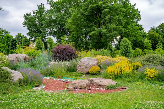 Collina alpina con erba verde lussureggiante. Prato e sentiero tortuoso in un bellissimo giardino in stile inglese.