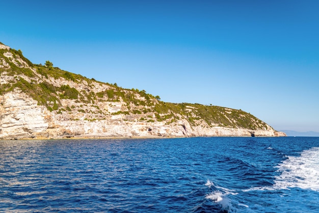 Collina coperta di piante con rocce sulla riva dell'isola di Corfù