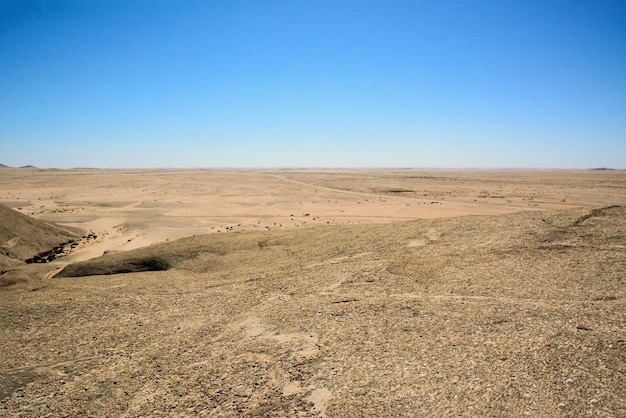 Colline aride del deserto con rocce fino all'orizzonte su uno sfondo di cielo blu