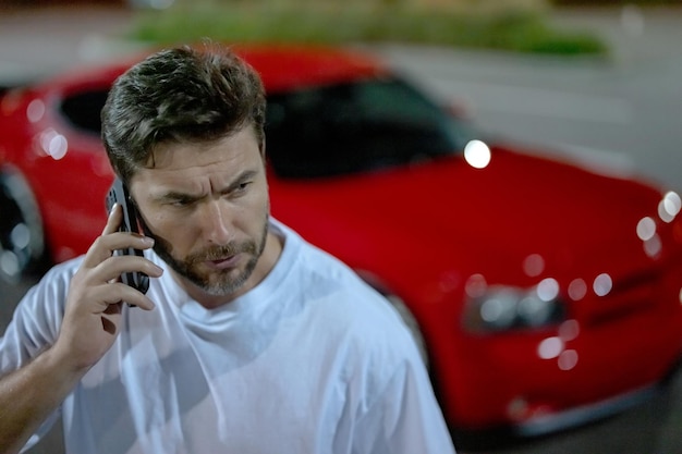 Colloquio aggressivo autista serio uomo che parla al telefono durante la notte strada urbana autista aggressivo discorso uomo