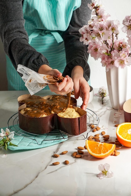 Colomba - tradizionale colomba pasquale italiana, processo di decorazione con glassa a base di nocciole, macaranage, spolverata di mandorle, mani di donna.