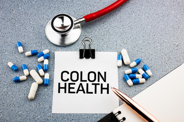 COLON HEALTH testo sulla scrivania del medico COLON HEALTH accanto a pillole e stetoscopio