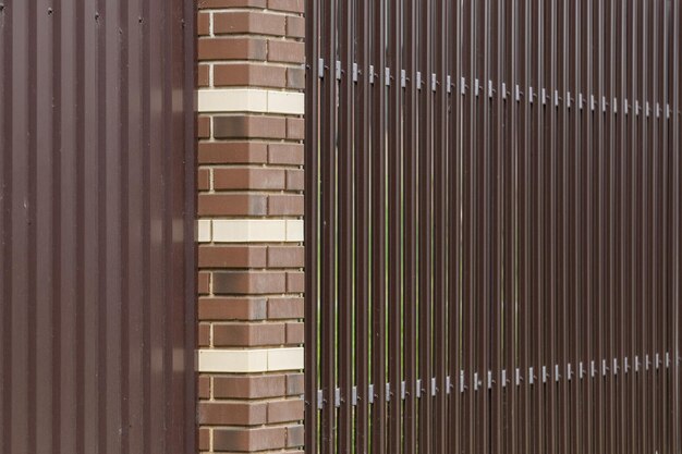 Colonna in mattoni con recinzione realizzata con profili in metallo marrone