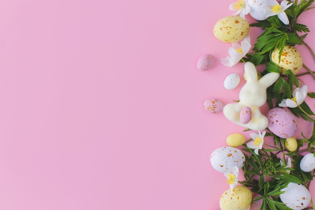 Colorate uova di cioccolato pasquali coniglietti e fiori primaverili bordo piatto giacevano su rosa Buona Pasqua