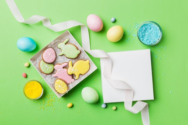 Colorati biscotti pasquali nel carrello con più colori Uova di Pasqua su sfondo colorato Colore pastello Uova di Pasqua Concetto di vacanza con spazio per la copia