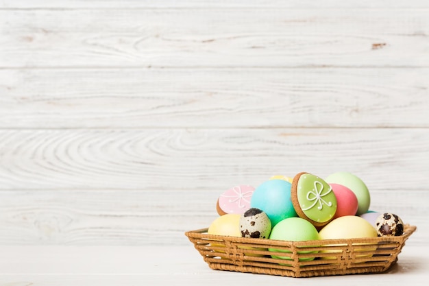 Colorati biscotti pasquali nel carrello con più colori Uova di Pasqua su sfondo colorato Colore pastello Uova di Pasqua Concetto di vacanza con spazio per la copia