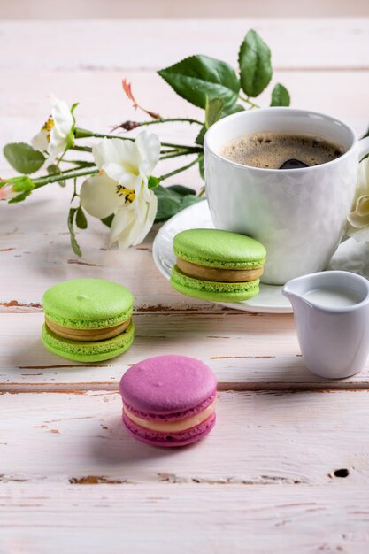 Colorati deliziosi biscotti francesi amaretti e una tazza bianca su un tavolo di legno Primo piano