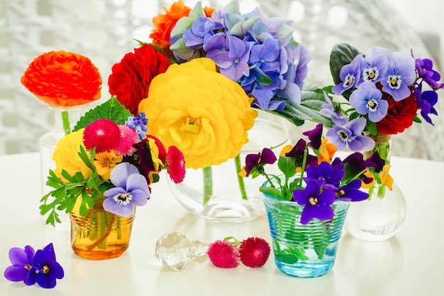 Colorati fiori appena tagliati in vasi di vetro sul tavolo bianco