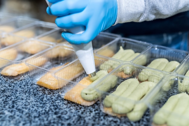 Colorato e delizioso dessert al pistacchio in confezione di plastica sul tavolo in fabbrica. Produzione industriale alimentare