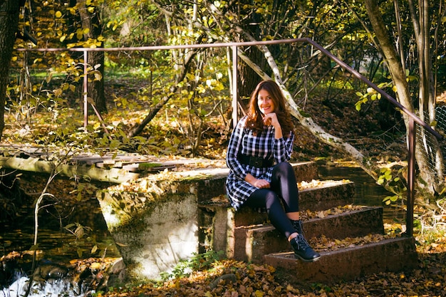 Colorato paesaggio autunnale con bella ragazza seduta sulle scale Concetto di viaggio e avventura